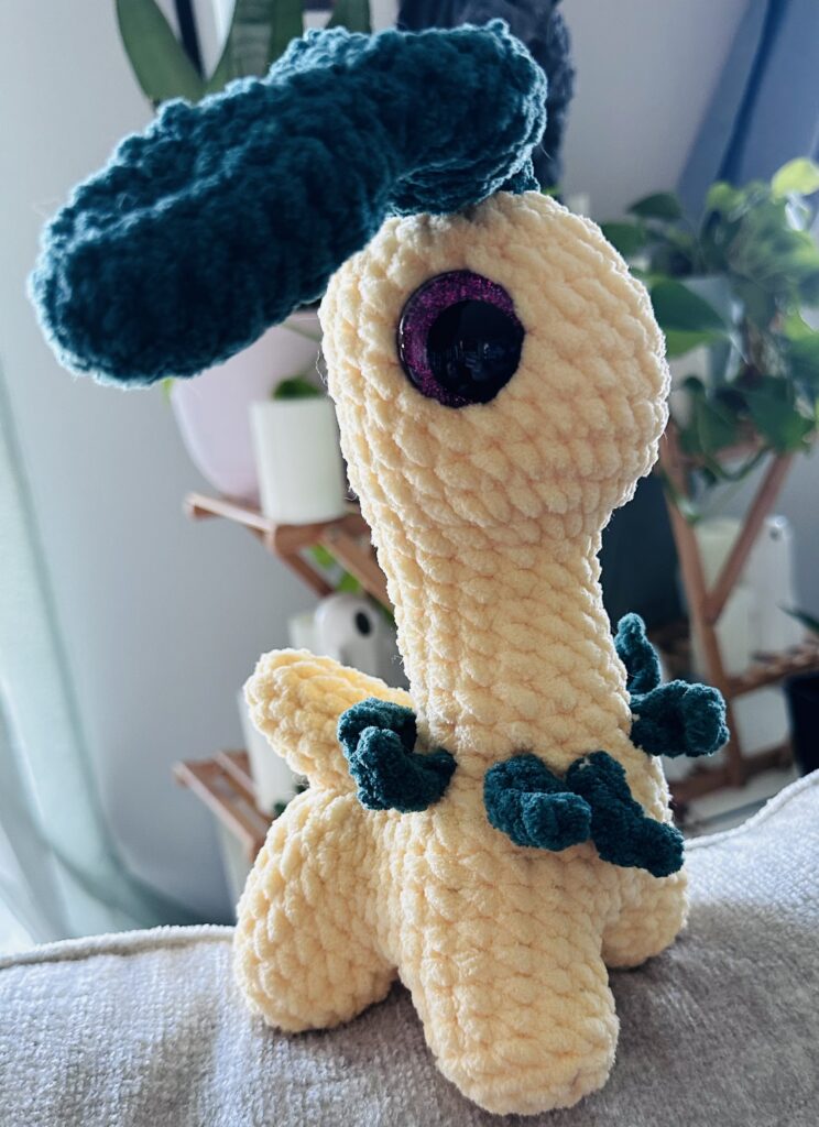 Yellow dinosaur with a green leaf on its head and green leaves on its neck